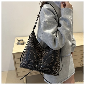 Detail of leopard print tote bag with black butterfly leather patch and lace-up design