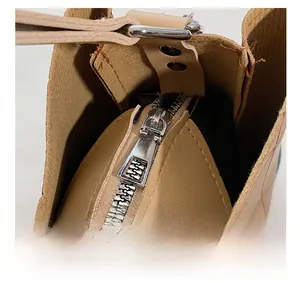 Detail shot of smooth silver zipper and lychee pattern faux leather on beige handbag