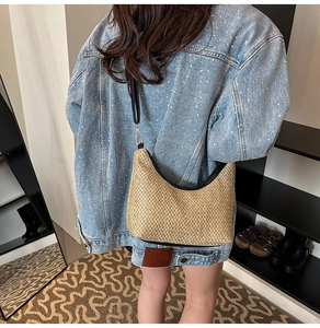 Detail of a chic straw shoulder bag featuring beige weave texture and black strap