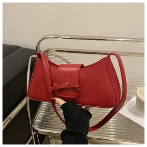 Detailansicht einer roten Schultertasche mit Schleife und glatter Lederoberfläche