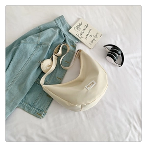 Vue à plat d'un sac besace en nylon blanc cassé avec bandoulière et mini porte-monnaie