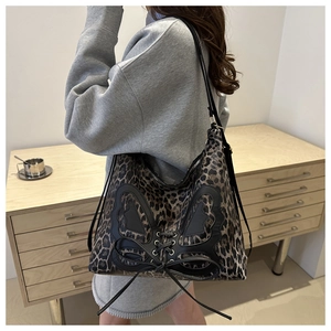 Detail of leopard print tote bag with black leather butterfly design and cross-lacing