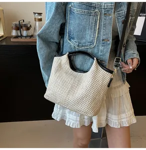 Detail of woven straw tote bag featuring black leather trim and gold metal buckles