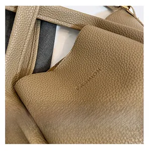 Macro detail of brown lychee grain leather bucket bag with embossed Fashion logo text