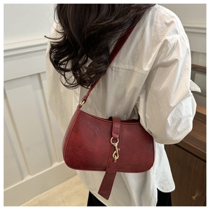 Close-up of vintage dark red underarm bag with golden hook buckle on textured leather