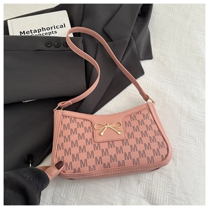 Pink bow shoulder bag with M letter print on elegant black blazer and decor book