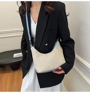 Close-up of woven tote bag with light blue leather trim and golden metal hooks