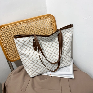 Retro monogram tote bag in cream and brown leather on a vintage rattan chair