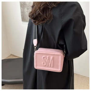 Detail of pink crossbody bag with SM embossed logo and striped wide shoulder strap