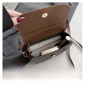 Gros plan sur la capacité intérieure du sac selle à motif vintage avec des objets du quotidien