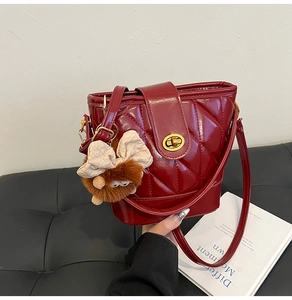 Détail du sac seau bordeaux en cuir verni matelassé avec fermoir doré et peluche