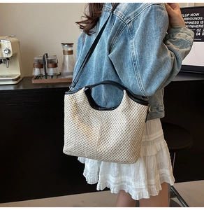 Outdoor street style shot of a straw woven bucket bag with black leather shoulder strap