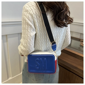 Detail of tricolor crossbody bag showing SM logo embossing and wide nylon strap