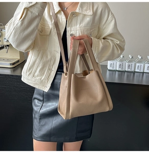 Detailed view of khaki pebbled leather texture and embossed fashion text on bucket bag