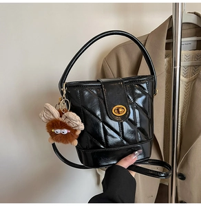 Détail du sac seau noir matelassé avec dorures et breloque monstre en peluche