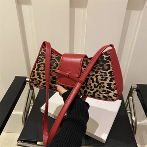 Leopard-Unterarmtasche mit rotem Lederbesatz und Schleifendetail in der Hand