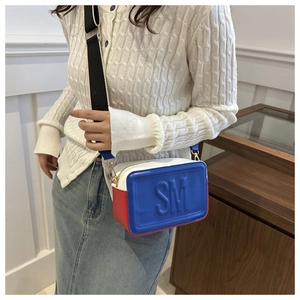 Detail of the tricolor crossbody bag featuring embossed SM logo and wide fabric strap
