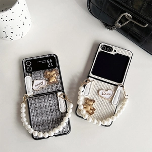 Detailed close-up of tweed folding phone case with bear charm and pearl handle