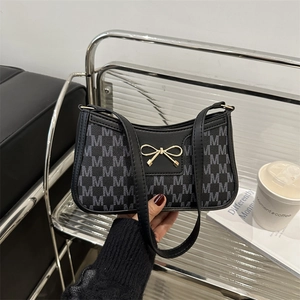 Fashionable monogram shoulder bag with gold bow clasp for chic urban commuting