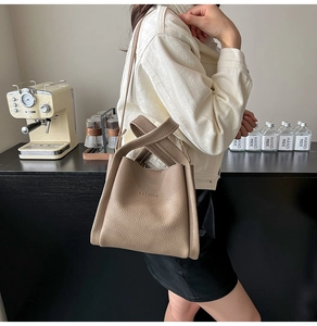 Detail showing litchi grain leather texture and embossed FASHION logo on bucket bag