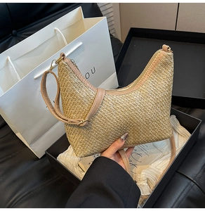 Close-up of woven straw crescent tote bag with pink leather trim and luxury box packaging