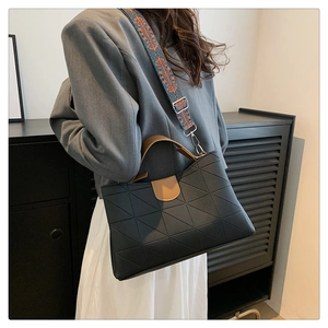 Detail of black quilted PU bag with brown handle and colorful embroidered strap