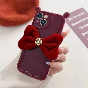 Close-up of wine red iPhone case featuring a velvet bow and golden rose detail