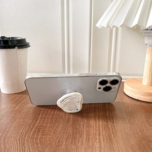Gros plan d'un support de téléphone blanc en forme de cœur sur un bureau en bois