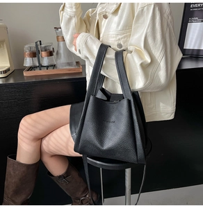 Detail of black lychee grain tote bag featuring embossed FASHION text and dual handles