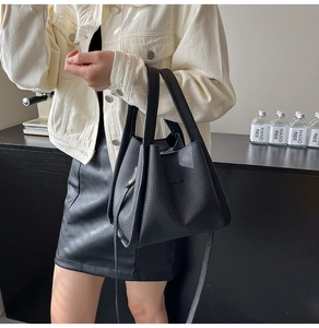 Macro detail of black litchi grain leather bucket bag with embossed Fashion logo