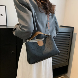 Detail of black quilted shoulder bag with contrast brown handle and ethnic wide strap