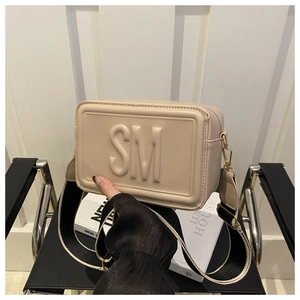 Detail of beige square crossbody bag with SM embossed logo and wide woven strap