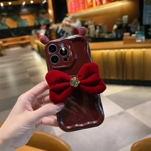 Wavy red iPhone case with velvet bow and gold rose relief in elegant cafe setting