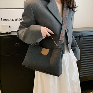 Detail of black quilted shoulder bag with contrast brown buckle and colorful ethnic strap