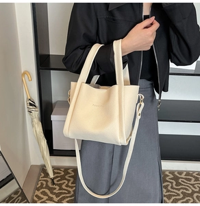 Detail of beige lychee pattern bucket bag with FASHION logo and adjustable strap