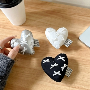Bow heart phone grip stand in black, white, and silver on a wooden desk setting