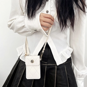 Detalle del bolso blanco acolchado para móvil con adorno de camelia y correa