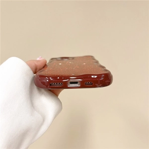 Close-up of wavy burgundy glitter phone case showing precision charging port cutouts