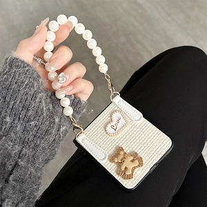 Detail of white woven Samsung Z Flip case with heart love patch and pearl handle