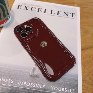 Close-up of wine red wavy phone case with golden rose floral accent on fashion magazine