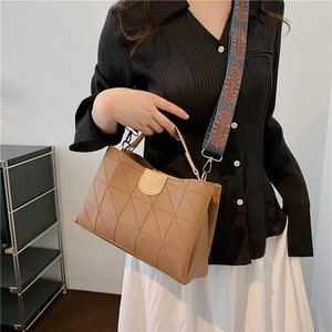 Detail view of khaki geometric embossed tote bag with colorful ethnic patterned wide strap