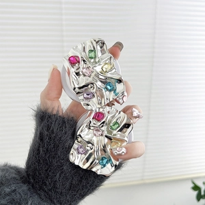 Close-up of metallic pleated phone grips with colorful rhinestones on a white base