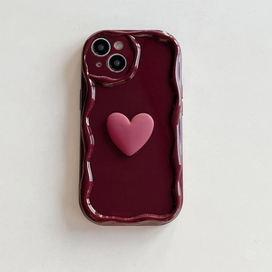 Close-up of deep red wave-edge iPhone case with a 3D pink silicone heart ornament