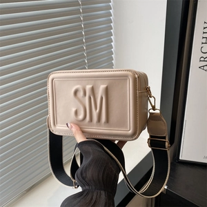 Minimalist beige crossbody bag with embossed SM letters and wide contrast shoulder strap