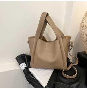 Detail of brown litchi pattern bucket bag with FASHION embossed logo and soft leather texture