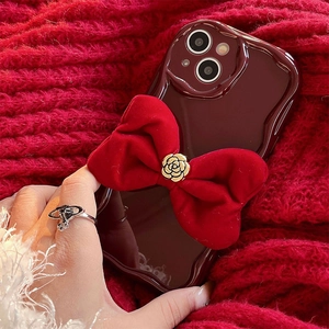 Close-up of a red velvet bow and golden rose buckle on a wave-edge iPhone case