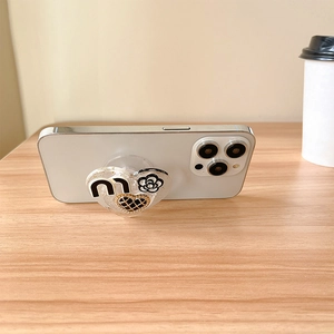 Détail d'un support de téléphone cœur en résine pailletée avec fleur de camélia