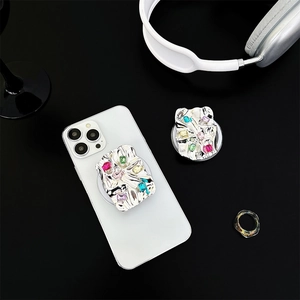 Silver metallic phone grip with colorful rhinestones on a white smartphone surface