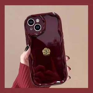 Detail of burgundy wavy edge phone case with a golden rose flower metal ornament