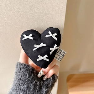 Close-up of black 3D fabric heart phone grip with white bows and creative label